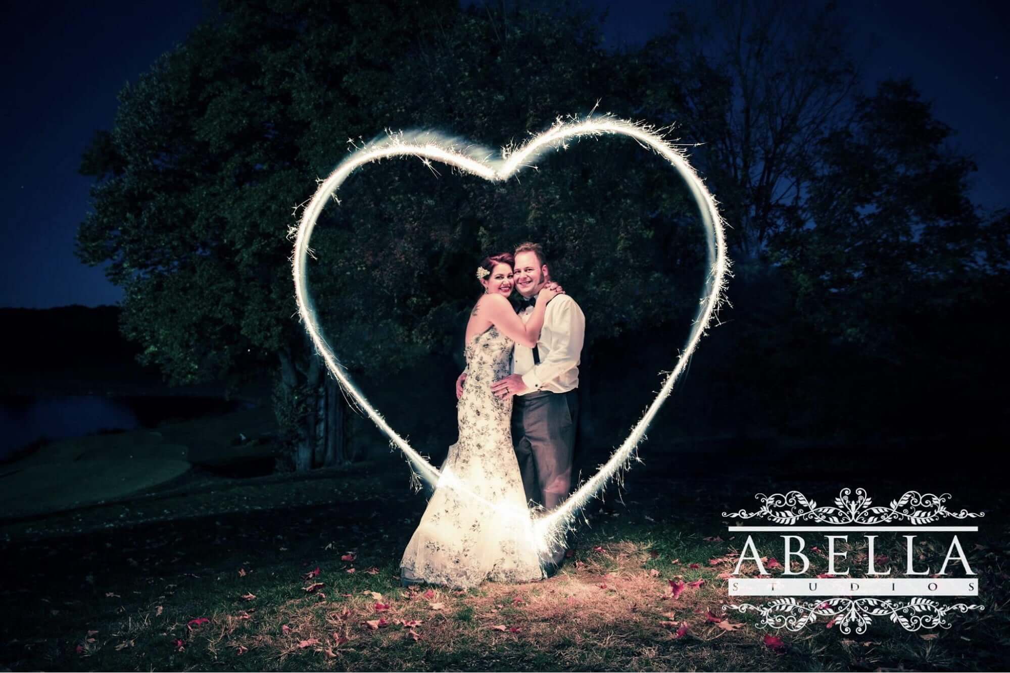 bride-groom-heart-sparkler Bride and Groom standing outside behind a heart sparkler