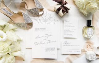 A variety of wedding items, including a wedding invitation and wedding shoes, are artfully arranged on a table at one of the exquisite Florham Park wedding venues in New Jersey.