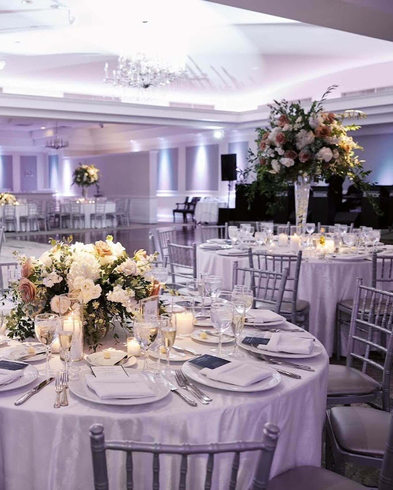wedding centerpieces Elegant banquet hall setup for kosher weddings in NJ with floral centerpieces and silver chiavari chairs.