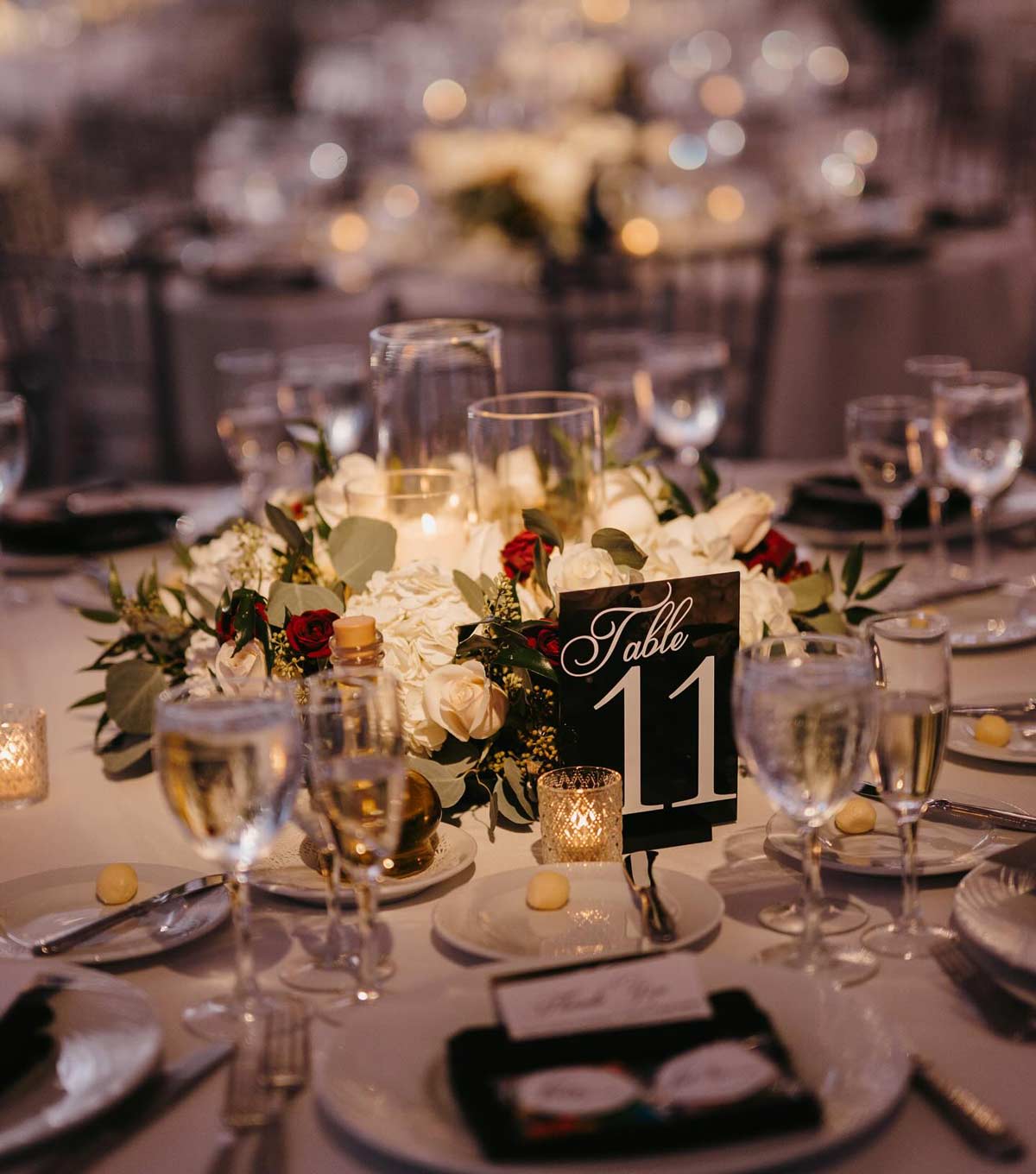 A wedding table setting labeled "Table 11" adorned with a floral centerpiece, candles, and elegant tableware serves as a beautiful reminder to celebrate love. Before you reach this special day, remember that getting your marriage license in NJ is one of the key steps in your journey.