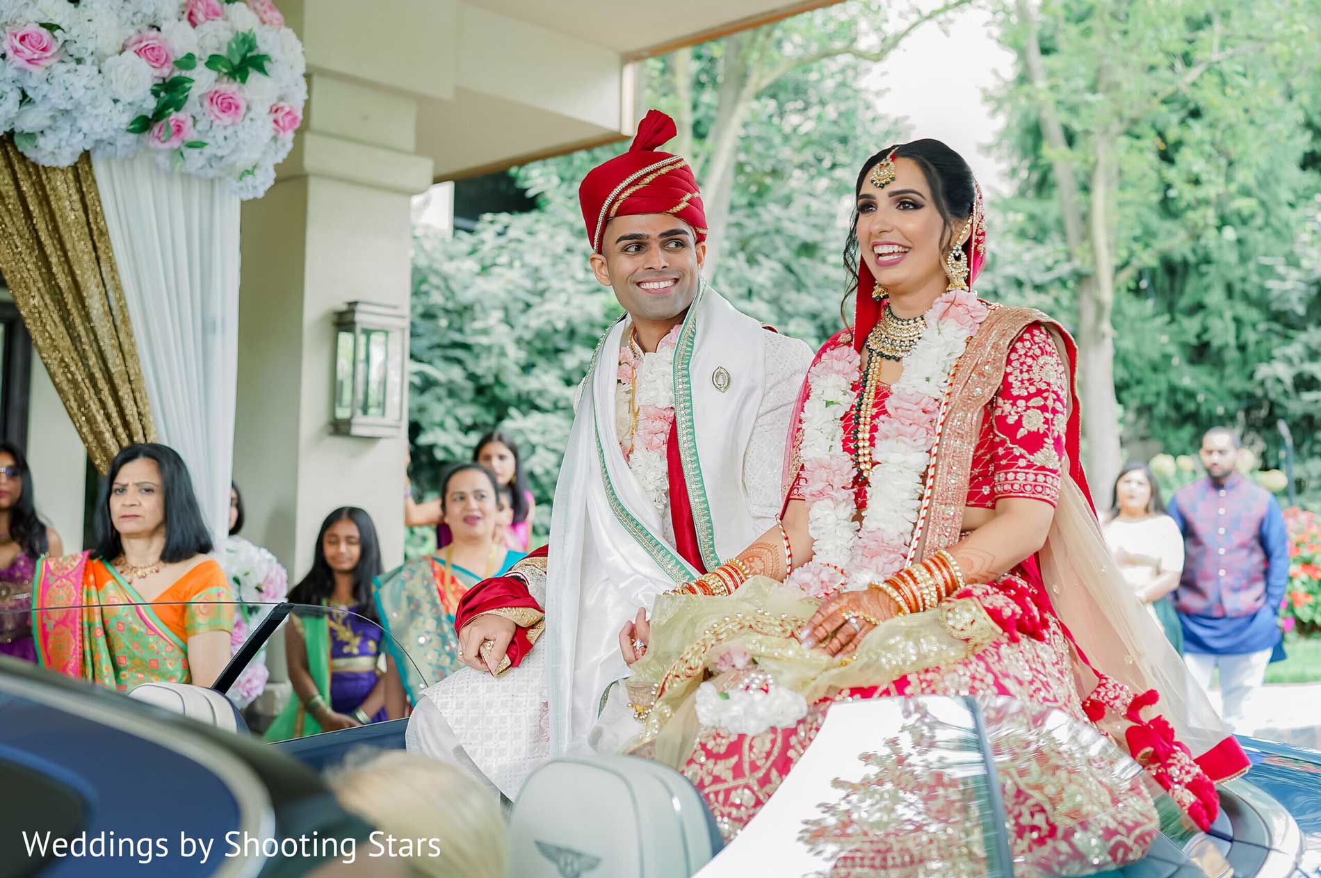 brooklake-352903-Nikita-Darshan-All-Edits-2nd-Half-53-orig A bride and groom in traditional Indian wedding attire sit together, smiling, during an outdoor wedding procession with guests in the background—capturing the vibrant spirit often seen at NJ Teen Events.